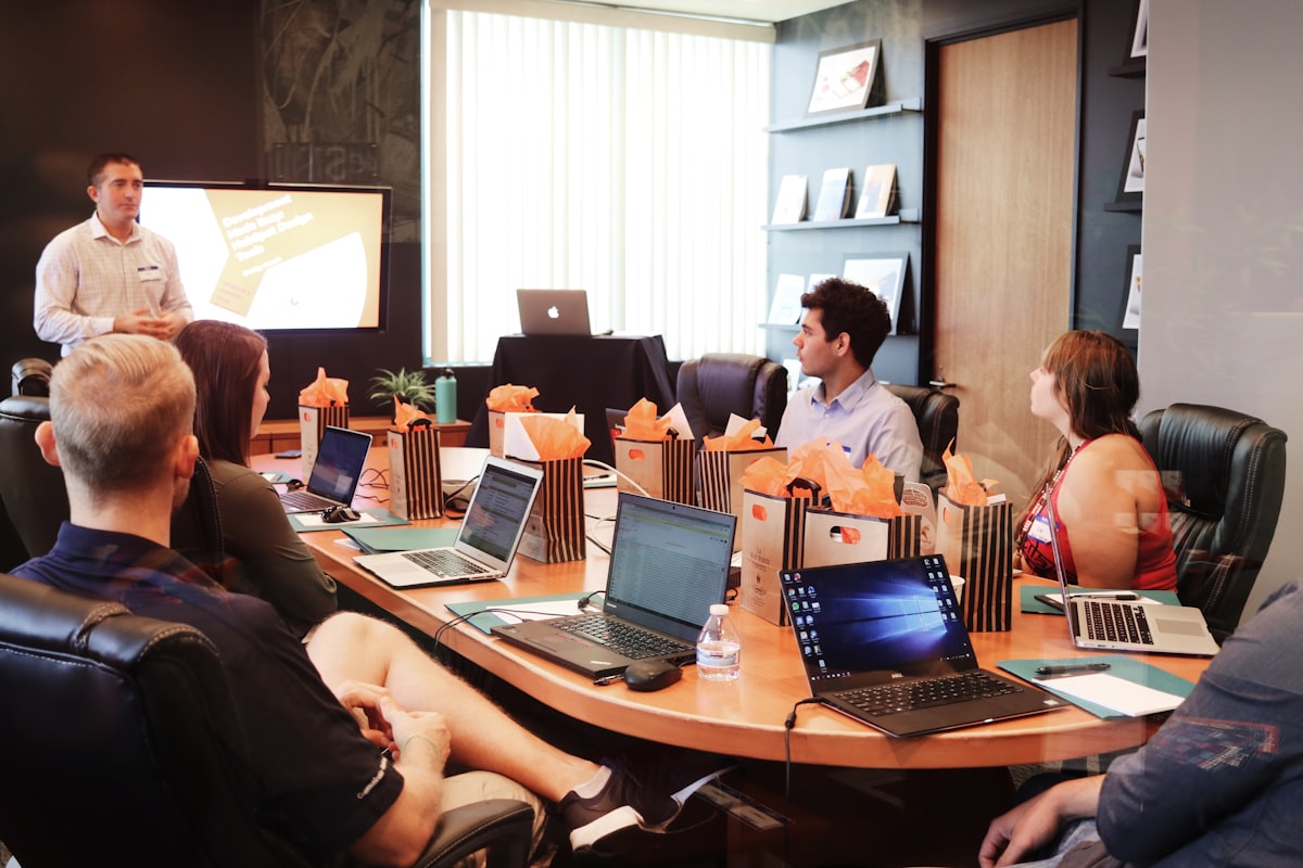 Team gathered around a conference table during a strategy workshop with laptops and a presentation screen
